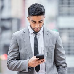 Shot of a young businessman using his smartphone while walking outside. Shot of a young businessman using his smartphone while walking outside.